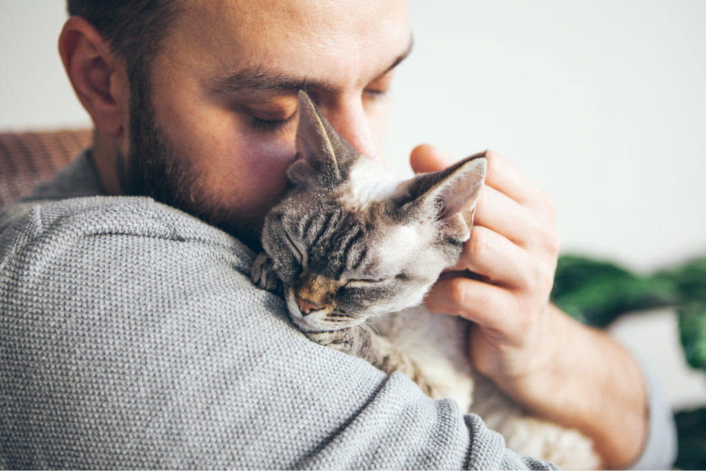 Man cuddling cat against chest