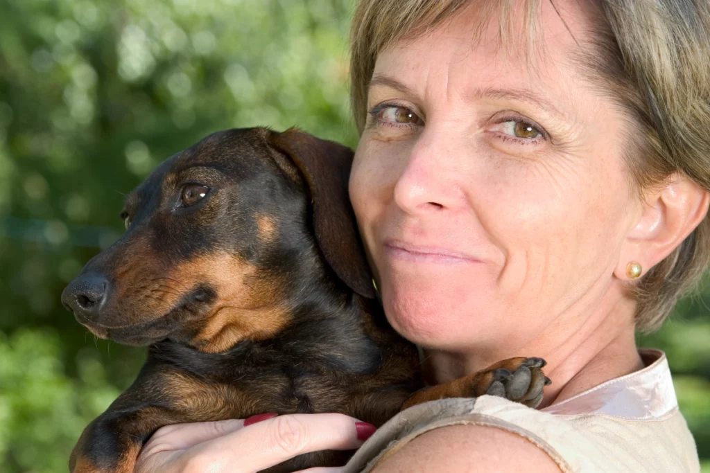 Mature woman smiling over her shoulder while holding a small dog