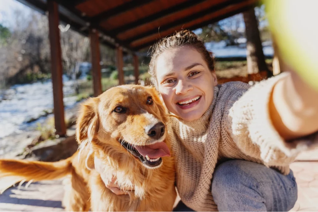 Pet sitter taking a selfie with golden retriever dog on an outdoor porch