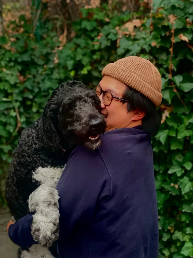 Candid photo of a PCI staff pet dad laughing while holding his dog, Oogi,